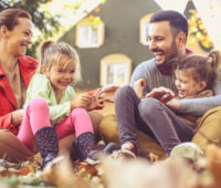 Little girls have fun with parents at backyard.