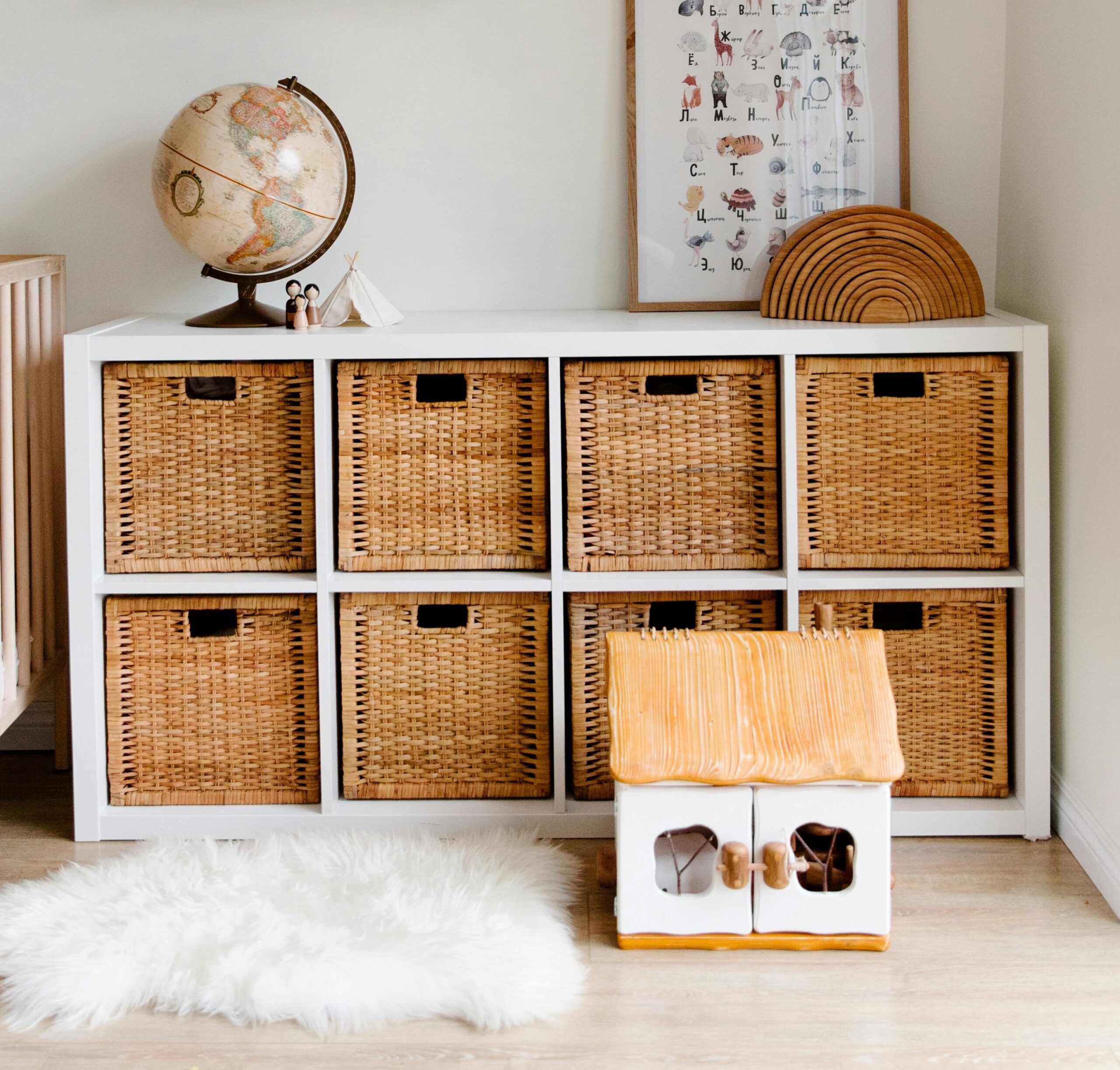 White shelf with woven storage boxes inside and a globe on top.