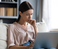 A homeowner doing research on a laptop about the NAR Settlement timeline