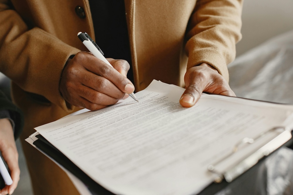 Person signing a document on a clipboard