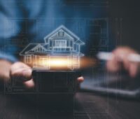 Hands holding a tablet with a glowing digital blueprint of a house overlayed, representing the integration of technology in modern real estate.