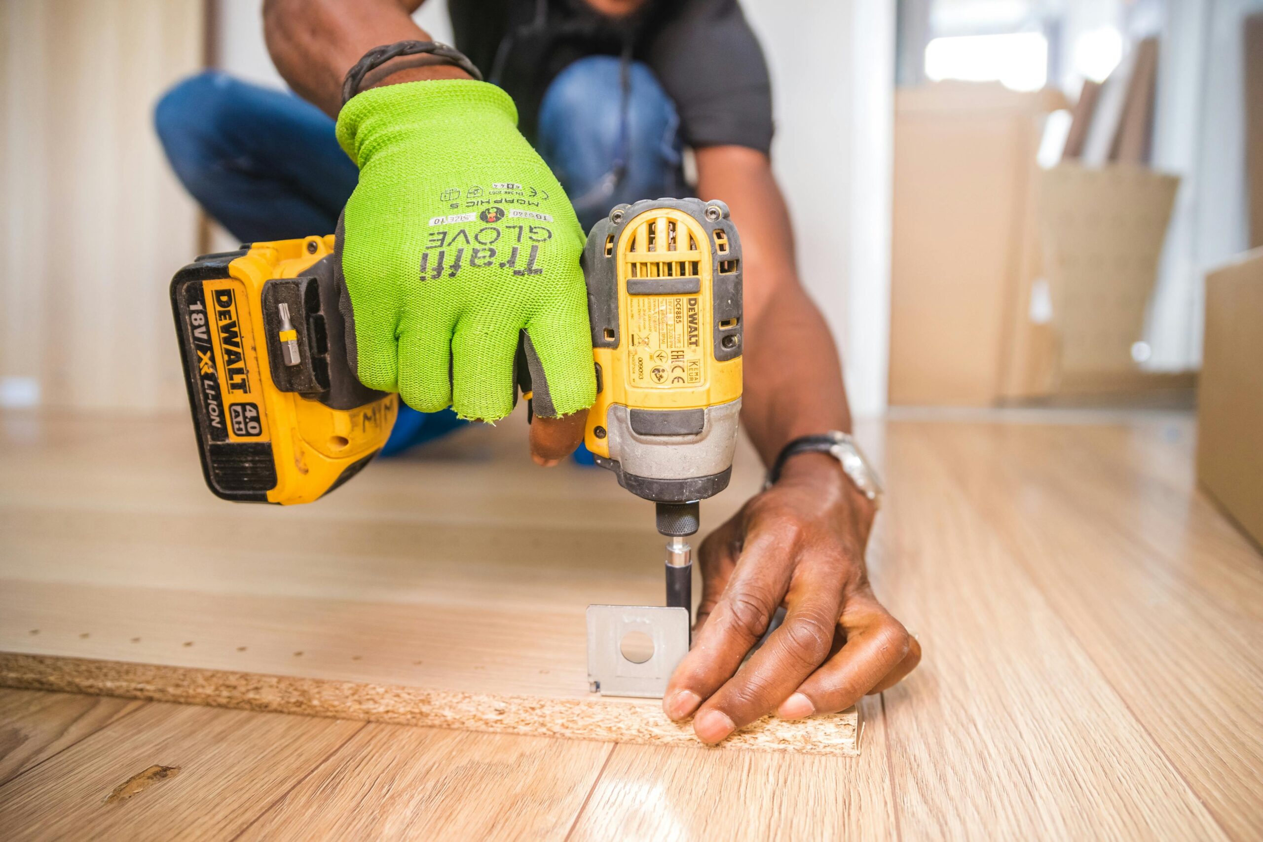 person attaching a bracket to a piece of wood with a drill