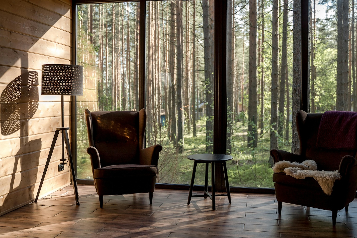 Living room with two chairs against a large window and a forest in the background.