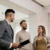 Couple standing next to a man in a suit inside a house.