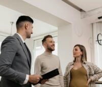 Couple standing next to a man in a suit inside a house.