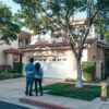 Couple standing in front of a house embracing each other.