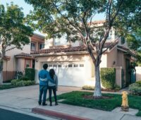 Couple standing in front of a house embracing each other.