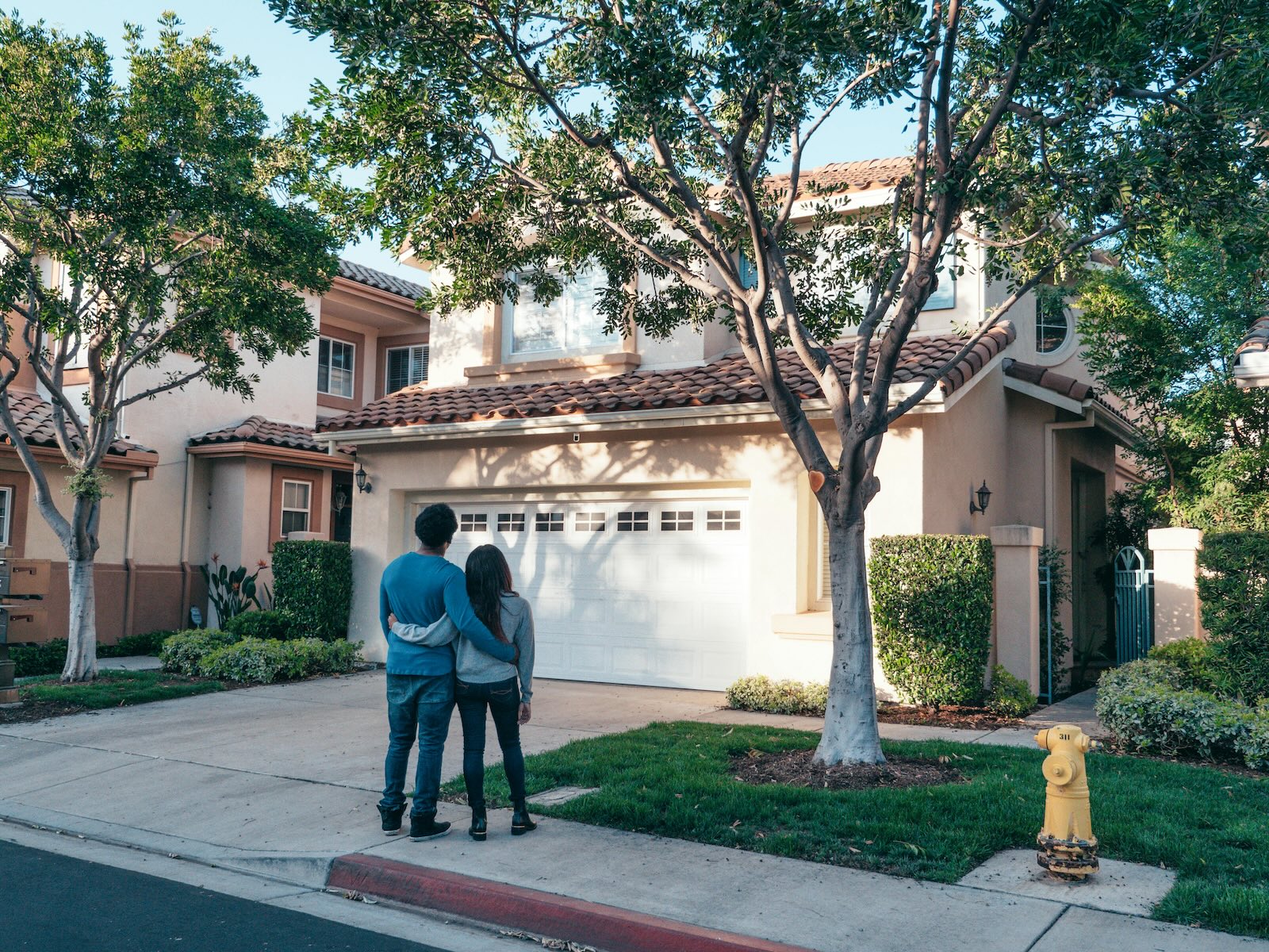 Couple standing in front of a house embracing each other.