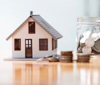 model home and jar of coins sitting on a table