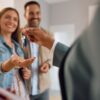 Close up of happy couple receiving keys of their new home from real estate agent.