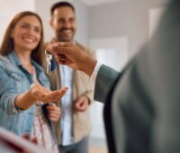 Close up of happy couple receiving keys of their new home from real estate agent.